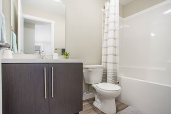 A white toilet sits next to a white bathtub in a bathroom.